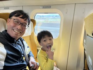 まちの車内でにっこり笑う親子。山形県東根市の土屋薬局の店主と息子さんが子どもの日に新幹線で過ごす様子