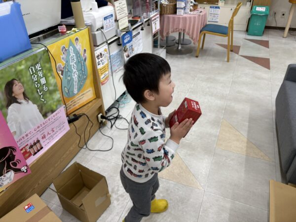 土屋薬局の店内でお店の品出しを手伝いをする４歳の息子です。にこにこしています。