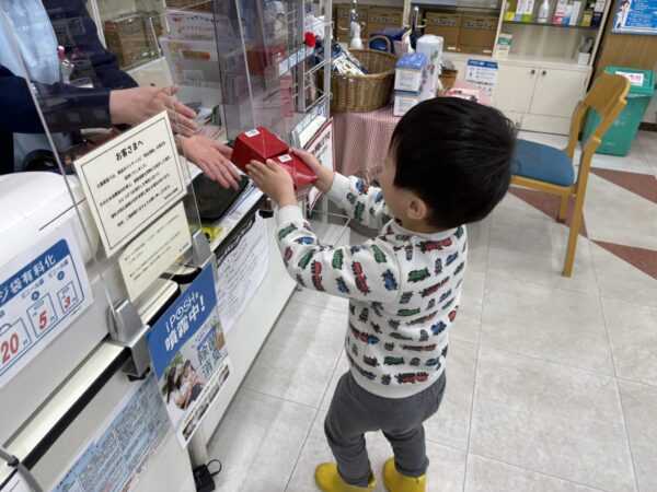 土屋薬局の店内でお店の品出しを手伝いをする４歳の息子です。にこにこしています。