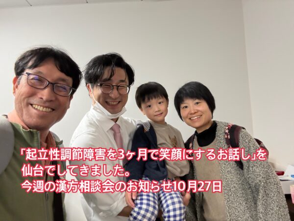 起立性調節障害の相談に対応する土屋薬局の土屋幸太郎薬剤師と、妻の土屋幸薬剤師、4歳の息子、イスクラ産業の担当者が笑顔で写っている写真。家族と地域の健康を支える温かい雰囲気。