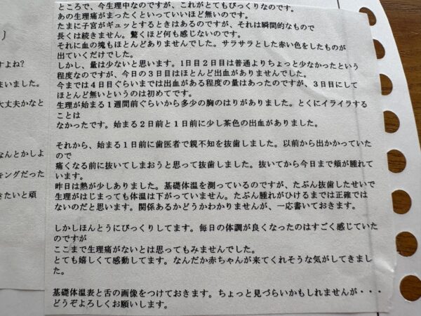 生理中の変化を詳細に記録した文章の写真。これまで強かった生理痛がほぼ消失し、子宮の軽い収縮以外は痛みがなく、血の塊も減少してサラサラした赤い経血が中心になったことが書かれている。出血量は1〜3日目で少なく、3日目にはほとんど出血がない点に驚いている様子。生理前の胸の張りや茶色の出血、親知らず抜歯後の腫れと発熱、基礎体温が高いまま推移している理由についての記録も含まれる。体調改善を実感し、妊娠への希望を感じている妊活中の女性の声が書かれた内容。