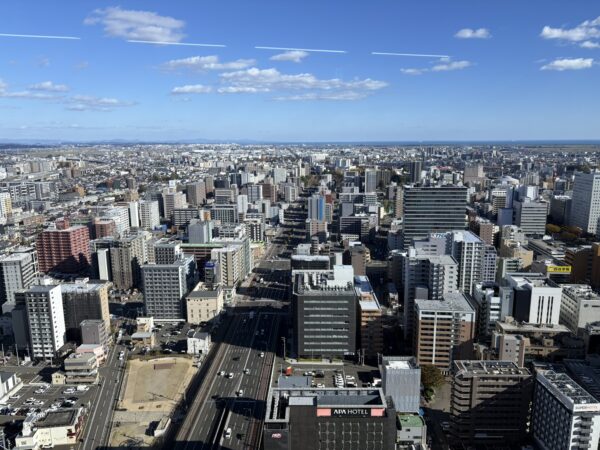 仙台アエル（AER）の高層階から見渡した仙台市中心部の風景。駅前のビル群と広がる街並みが一望できる、夕景のような落ち着いた眺望写真。