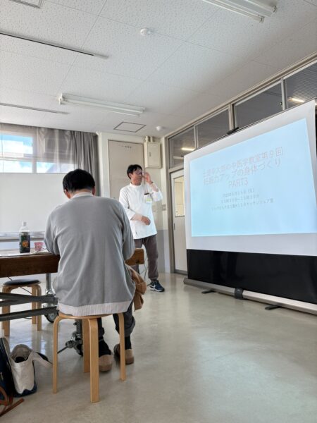 妊活と漢方の講演会で、講師が前方に立って参加者に向けて中医学の体質改善について説明している写真。」