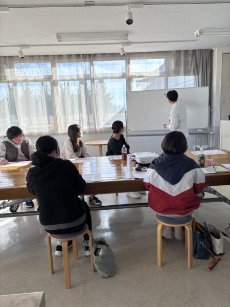 妊娠しやすい体づくりについて解説する講師が、教室前で中医学と漢方を用いた男性不妊・女性不妊の体質改善を説明している講演会の写真。