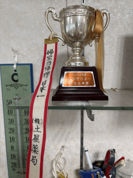 土屋薬局が2004年に受賞した婦宝当帰膠販売日本一のトロフィー。中医学の実践を通じて多くの女性の健康を支えてきた実績を示す記念の盾。