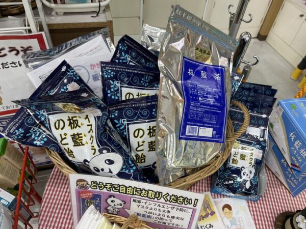 土屋薬局の店内で山積みになった板藍のど飴と板藍茶の陳列。冬の感染症対策に人気の板藍根商品が並ぶ様子。