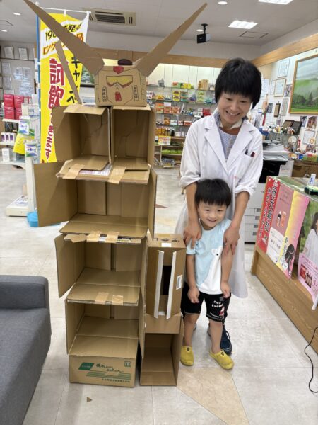 段ボールロボットの隣で、妻と息子が並んで微笑む親子の写真。