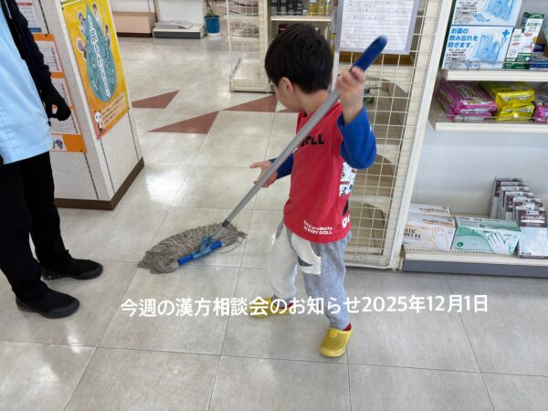 土屋薬局の店内で、年少さんの息子が朝の清掃として床をモップ掛けしている様子を写した写真。小さな体で一生懸命にお手伝いする姿が温かい家族経営の雰囲気を伝えている。