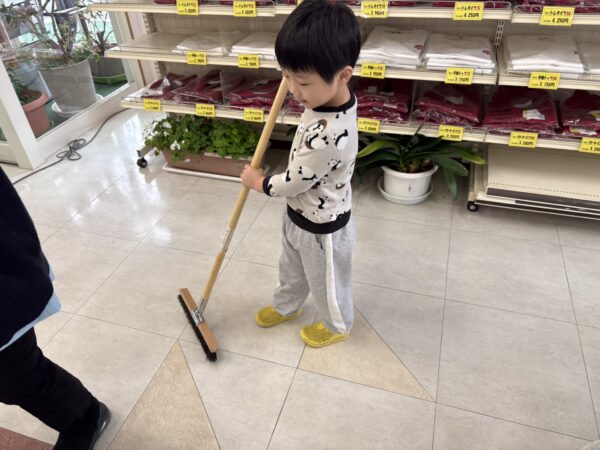 年明けの薬局で、子どもがモップがけを手伝っている様子。地域に根ざした薬局の日常風景
