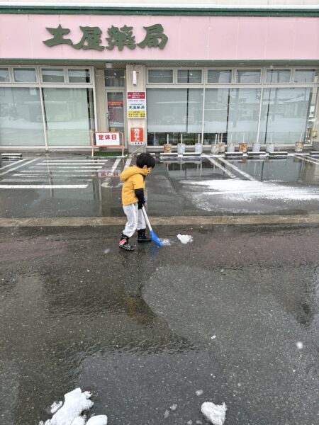 土屋薬局の駐車場で、日曜日の休みに雪かきを手伝う息子の様子