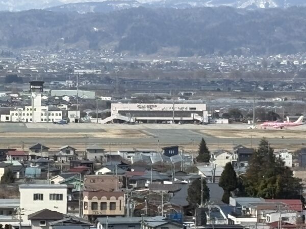 若木山から眺めた山形空港と、ピンク色のピーチの飛行機