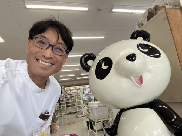 白衣姿の薬剤師・認定不妊カウンセラー土屋幸太郎とパンダのぬいぐるみ