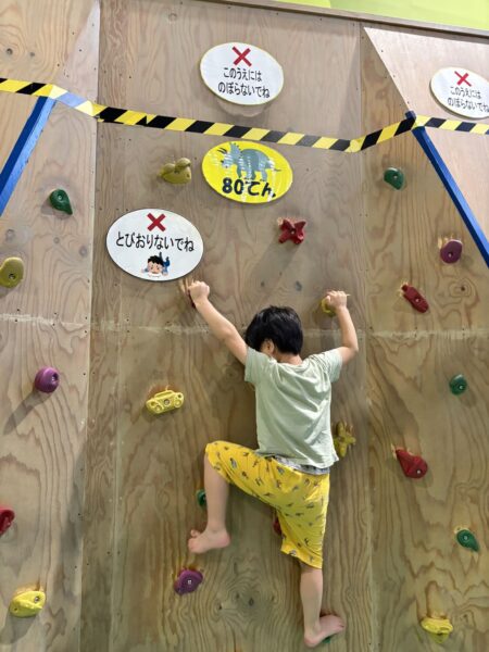令和8年7月9日、天童市の屋内遊び場「げんキッズ」でクライミングウォールに挑戦する5歳の息子。
