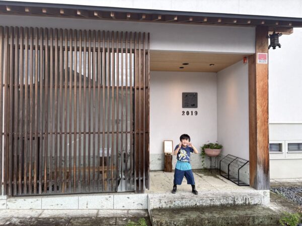 東根市のナガトロ美術館を訪れ、入口前でにっこりポーズをする5歳の息子。開館3年目の展覧会を家族で楽しみました。