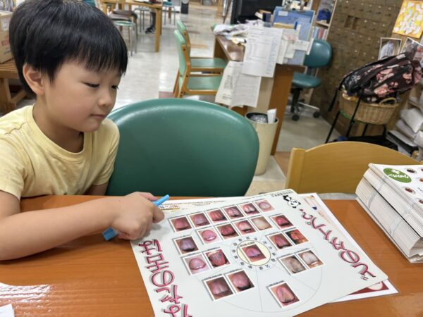漢方コーナーで舌診の写真を興味深そうに見つめる5歳の息子