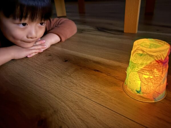 夜、部屋の電気を消して、手作りのランタンの明かりを見つめる息子
