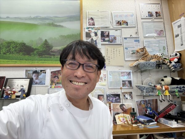 土屋薬局の漢方相談コーナーで、白衣を着て笑顔を見せる薬剤師・土屋幸太郎