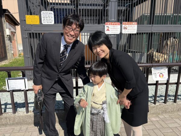 谷地動物園のツキノワグマ「つむぎちゃん」の前で撮影した家族3人の記念写真